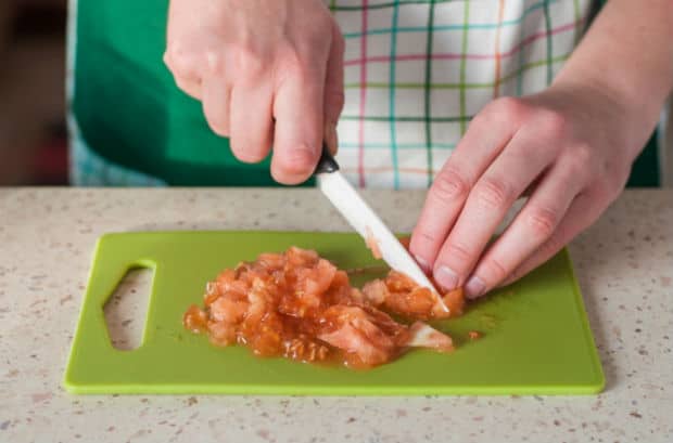 нарезанная мякоть помидоров на зеленой разделочной доске с ножом на столе