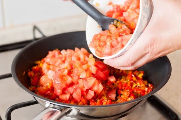нарезанные помидоры перекладываются в сковороду с овощами на плите