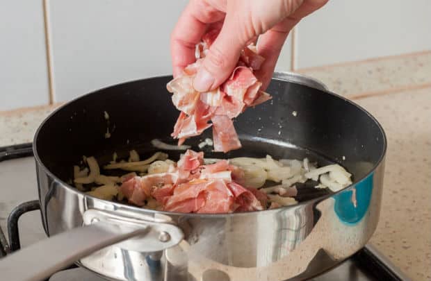 нарезанный бекон добавляется в сковороду с луком