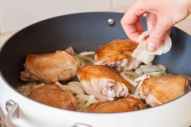 нарезанный лук добавляется в сковороду с обжаренными куриными бедрышками