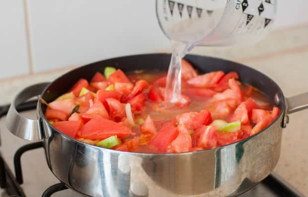вода вливается в сковороду с помидорами и кабачками