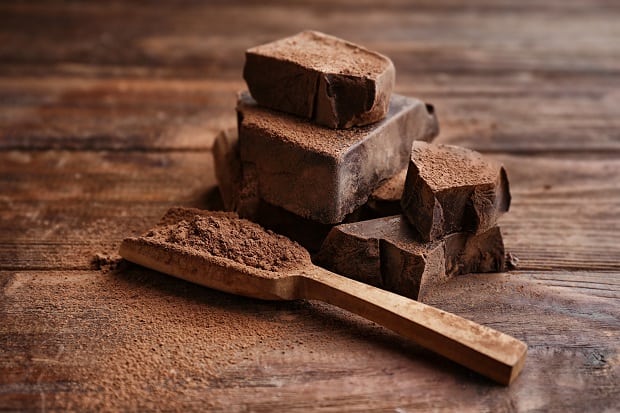 кусочки горького шоколада и шоколадный порошок в деревяннйо лопатке
