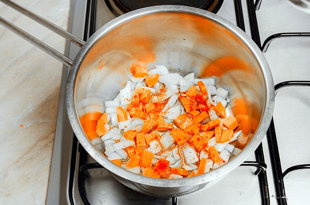 нарезанные лук и морковь в сотейнике на плите