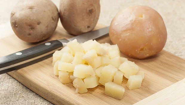 целая и нарезанная отварная картошка с ножом на доске