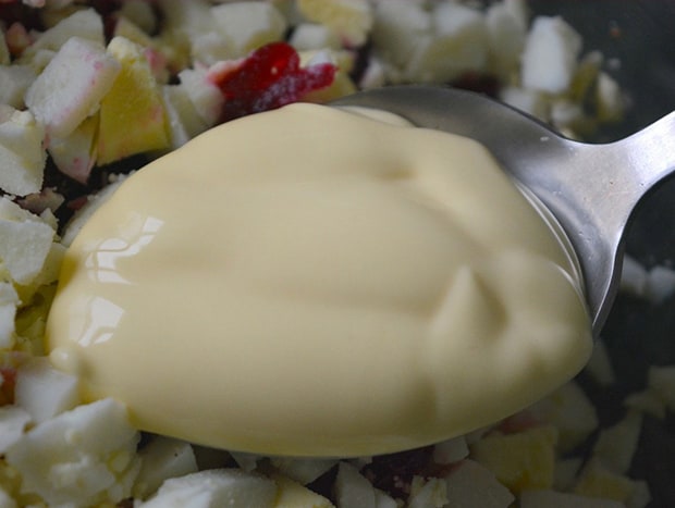йогурт в ложке над нарезанными яйцами со свеклой